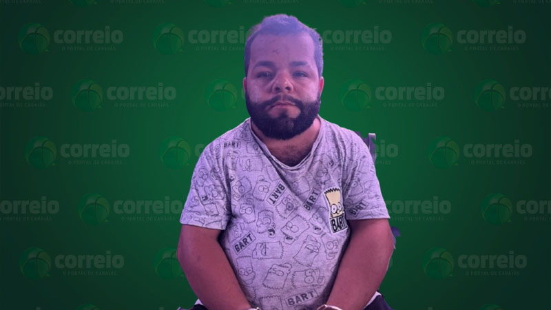 Homem barbudo com camiseta do Bart Simpson e algemas em frente a um fundo verde com logos 'correio'.