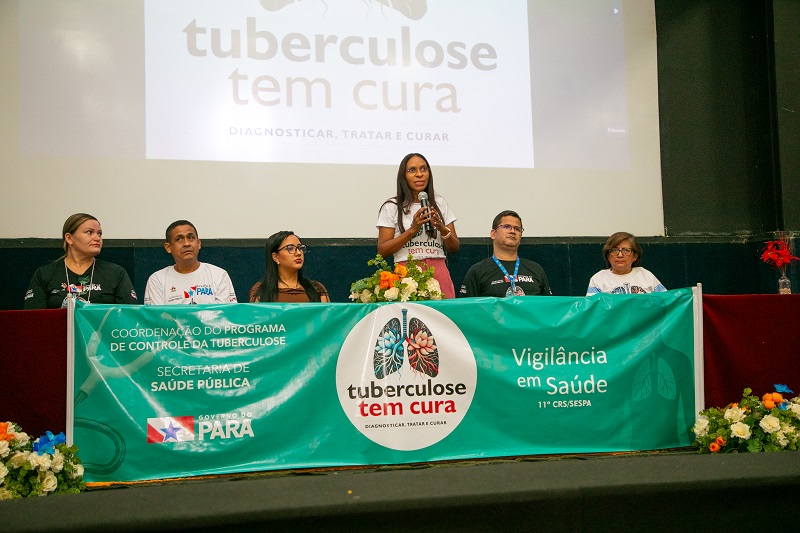 Mulher discursando em um painel de debate sobre o Programa de Controle da Tuberculose no Pará.