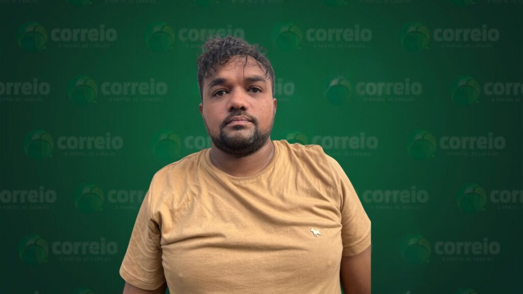 Homem com cabelo escuro e barba, vestindo camiseta mostarda, em frente a um fundo verde com logos 'correio'.