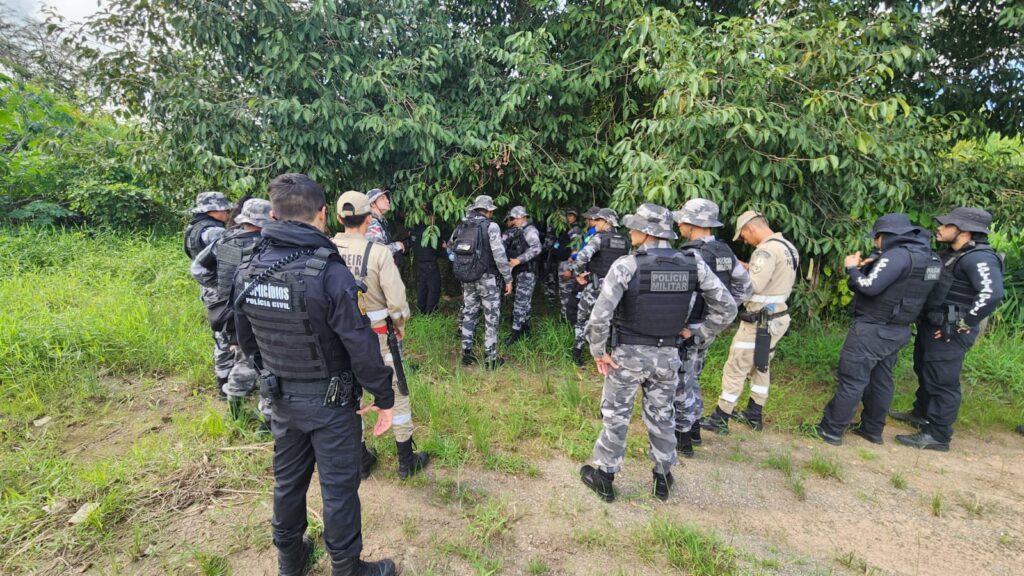 Grupo de policiais militares e civis em operação em área de mata fechada.