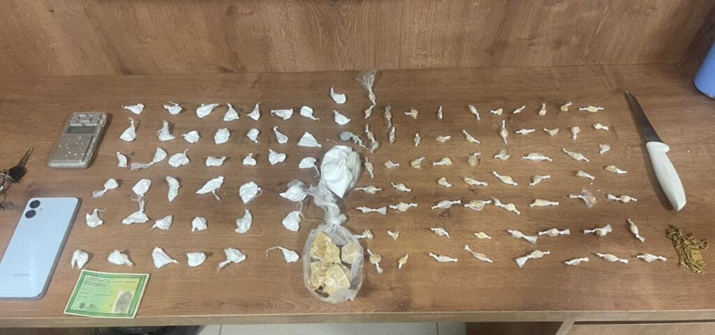 Drogas ilícitas apreendidas, incluindo cocaína e crack, sobre uma mesa de madeira.