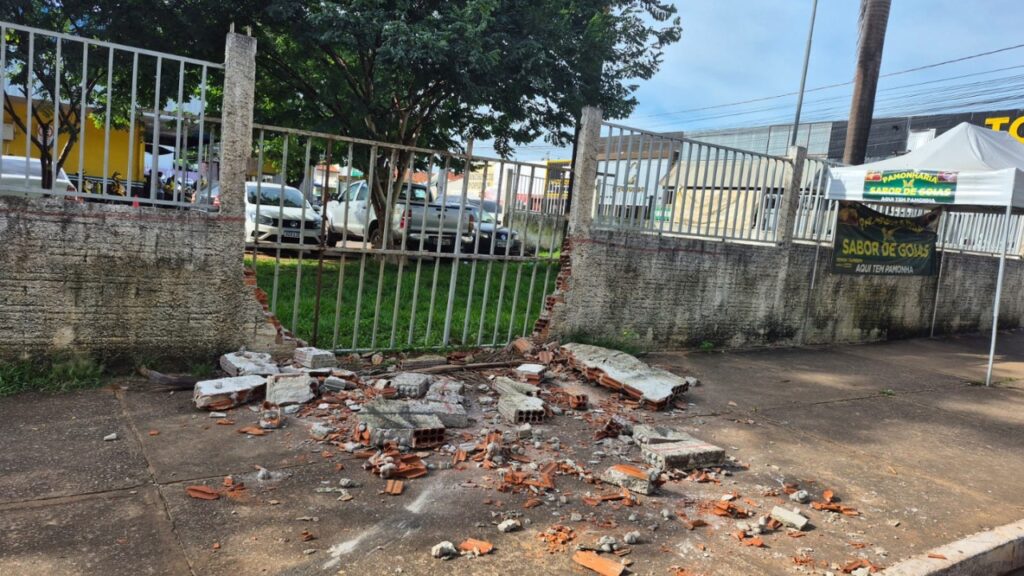 Muro de concreto e grade de metal quebrados com entulho na calçada.