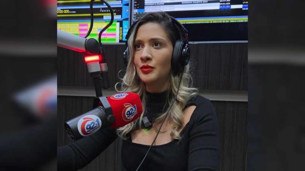 Mulher em estúdio de rádio com fones de ouvido e microfone da 92.1 Correio.