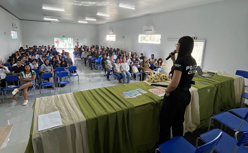 Mulher da Polícia Civil falando em evento para estudantes.