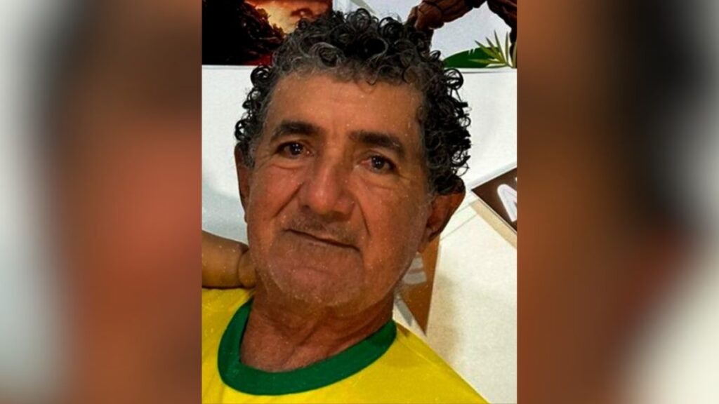 Homem com cabelos cacheados e camisa amarela com gola verde.