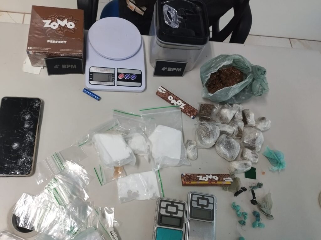 Mesa com drogas apreendidas, balanças e embalagens de papel de enrolar.