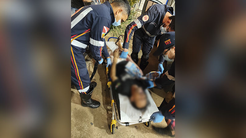 Membros da equipe SAMU prestando socorro a uma pessoa em maca.