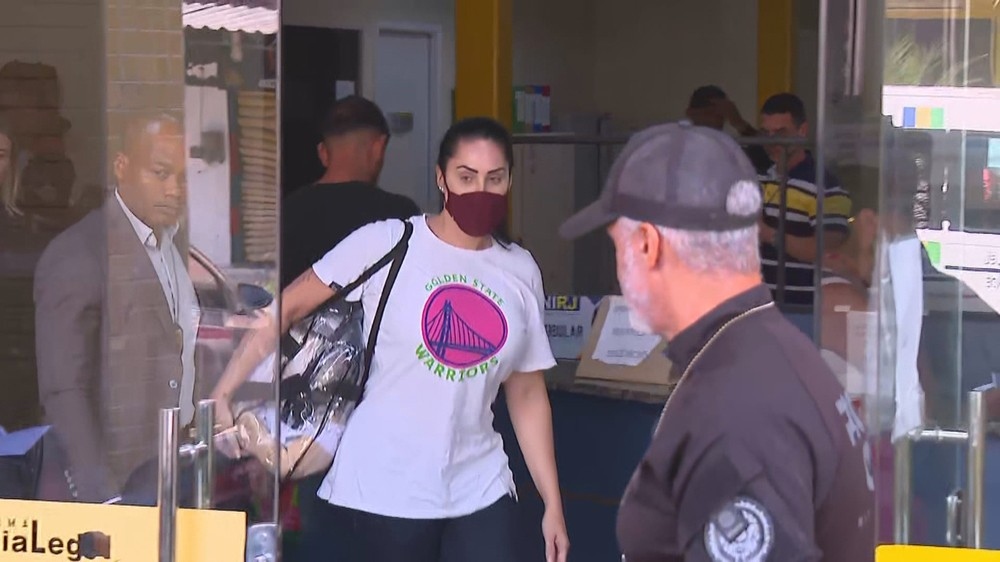 Mulher de máscara e camiseta Golden State Warriors entrando em local.