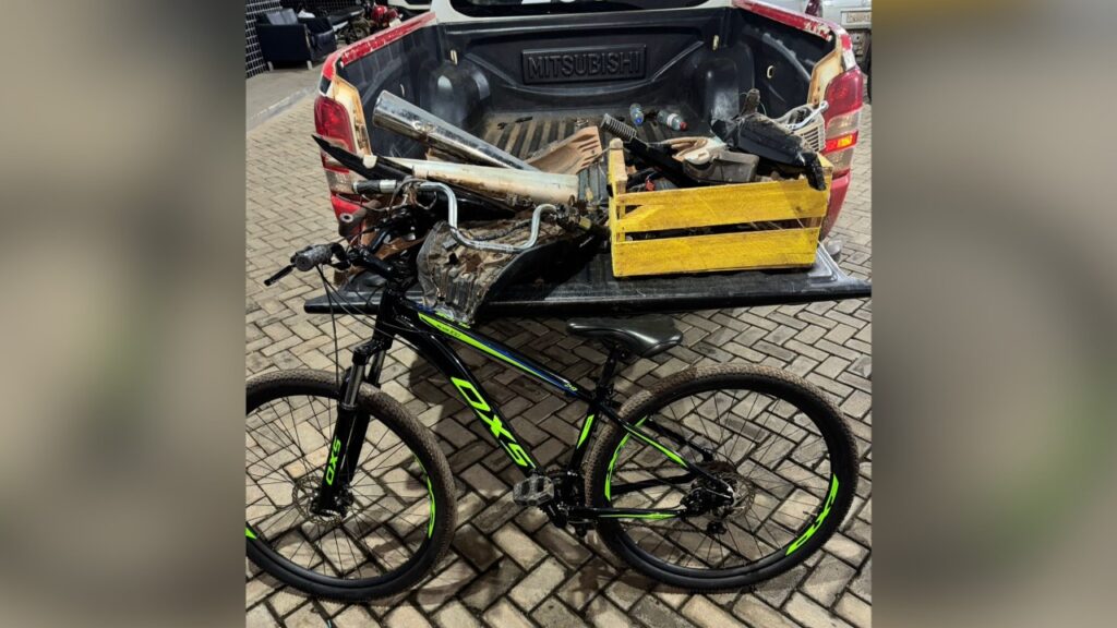 Bicicleta preta e verde com caçamba de picape Mitsubishi cheia de peças.