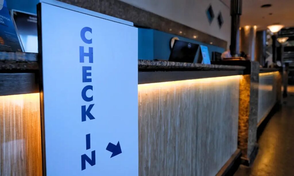 Placa de 'CHECK-IN' com seta em uma recepção iluminada.