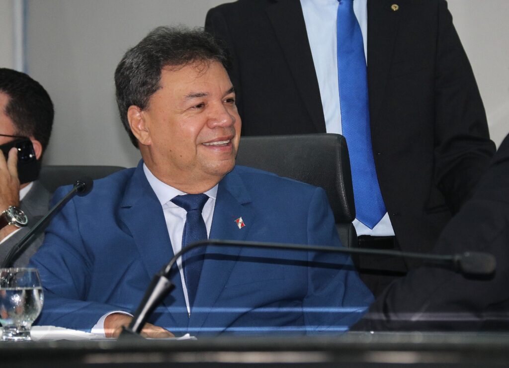 Homem de terno azul sorrindo em reunião formal.
