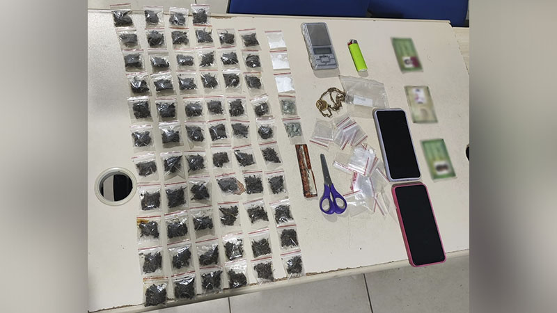 Mesa com diversas drogas embaladas, balança de precisão, celulares e outros itens apreendidos em operação policial.