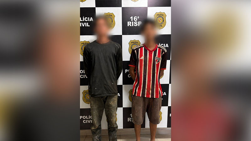 Dois homens com rostos borrados em frente a uma parede da Polícia Civil.