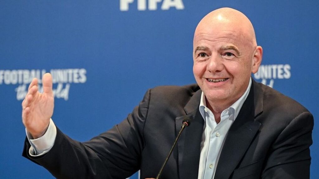 Gianni Infantino, presidente da FIFA, sorrindo e olhando para o lado em coletiva de imprensa.