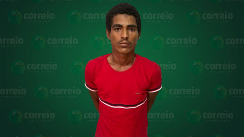 Homem de camiseta vermelha em frente a um fundo verde.