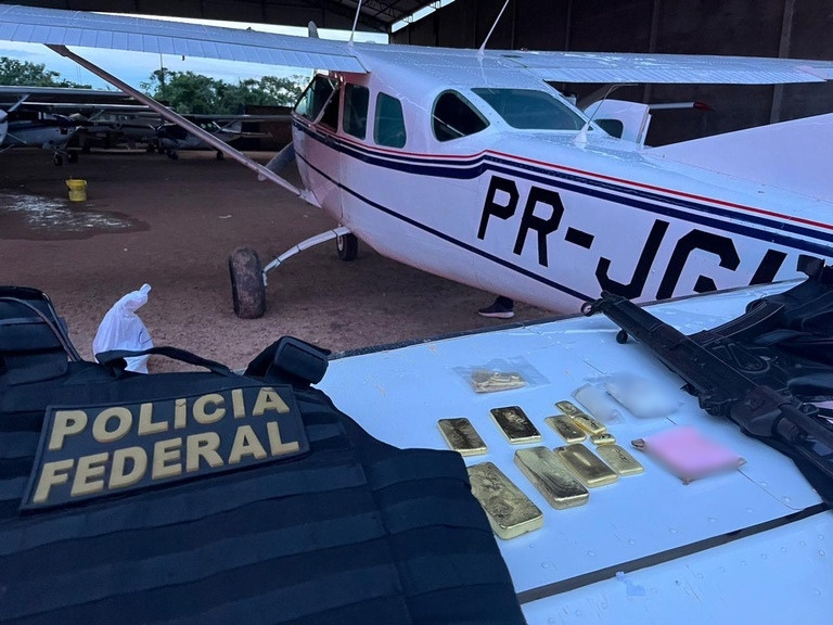 Operação da Polícia Federal exibindo apreensão de barras de ouro, drogas e um avião em hangar.