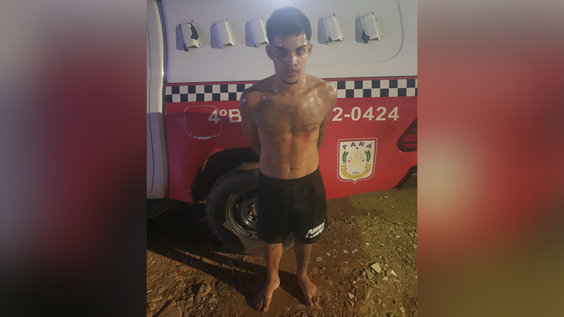 Jovem sem camisa e descalço em frente a uma viatura da Polícia Militar do Pará.