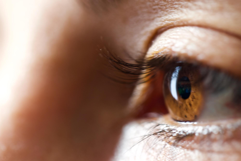 Olho humano castanho em close-up com cílios longos.