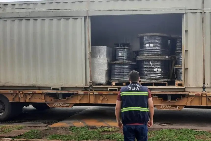 Fiscal da SEFA inspecionando carga de grandes bobinas de cabos em um contêiner.