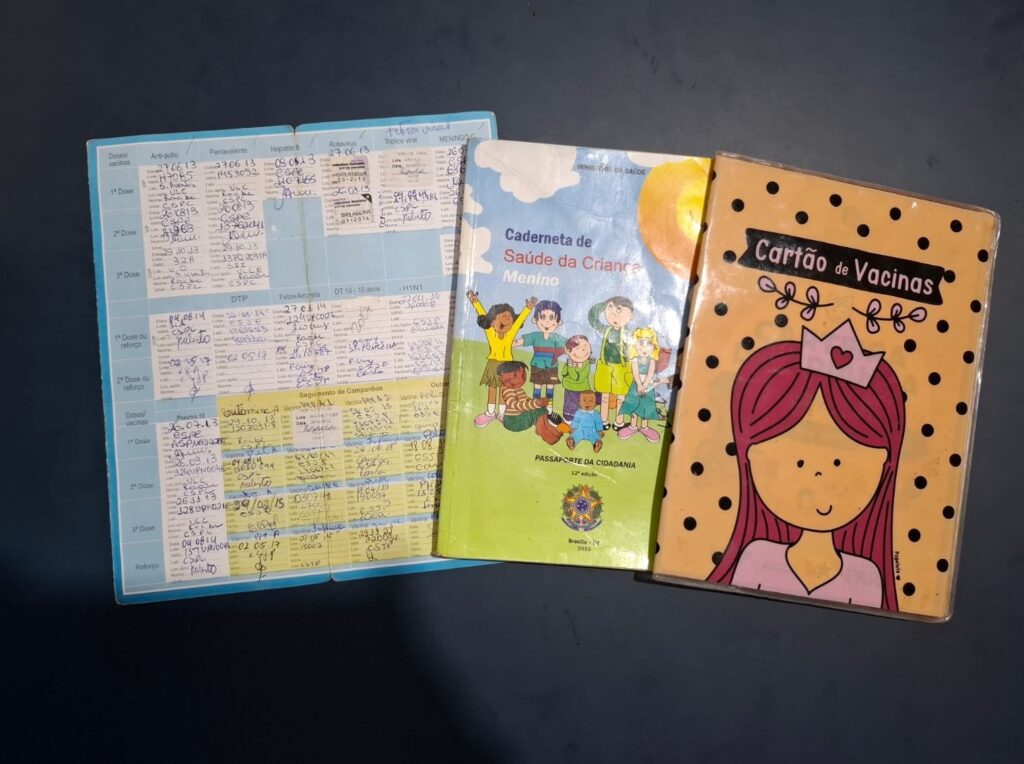 Documentos de saúde e vacinação infantil, incluindo Caderneta de Saúde da Criança e Cartão de Vacina.