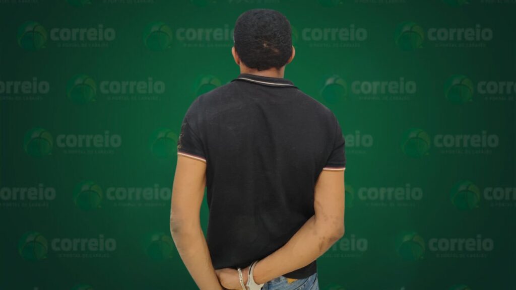 Homem de costas, algemado, vestindo camiseta polo preta e calça jeans.