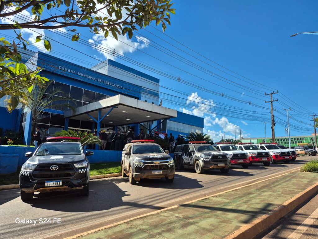 Frente da Câmara Municipal de Parauapebas com diversos veículos policiais estacionados sob céu azul.