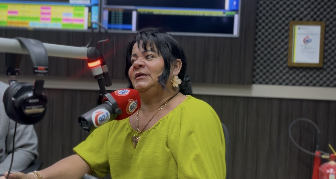 Mulher em estúdio de rádio com microfone profissional e fones de ouvido.