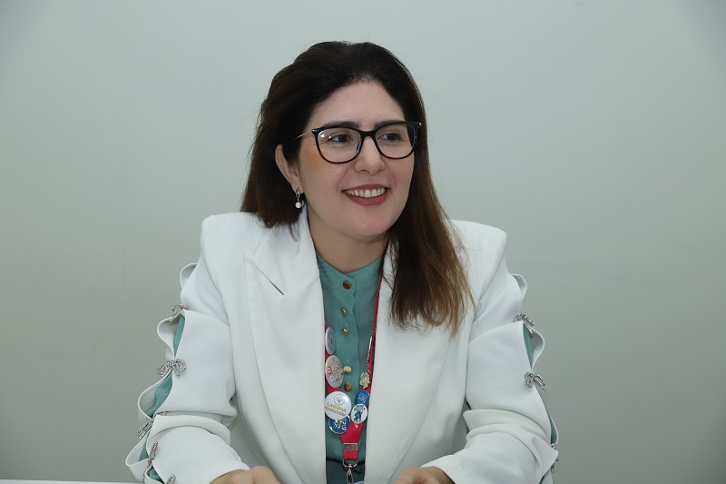 Mulher sorrindo com blazer branco e óculos