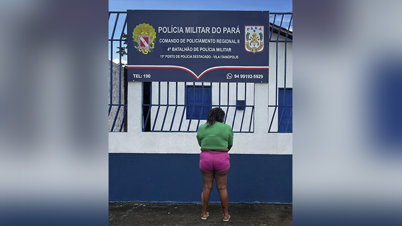 Pessoa de costas em frente a um posto da Polícia Militar do Pará, com placa de identificação visível.