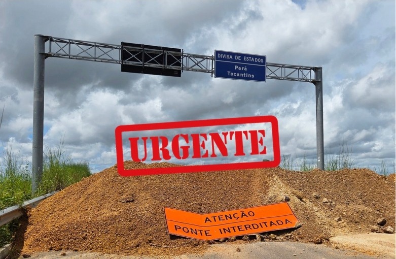 Placa de divisa entre Pará e Tocantins sobre uma estrada bloqueada por terra e com avisos de 'URGENTE' e 'PONTE INTERDITADA'.