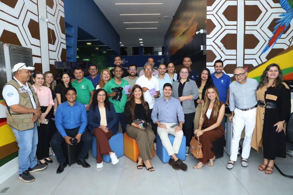 Grupo diverso de profissionais sorrindo e posando em um ambiente moderno de escritório ou evento.