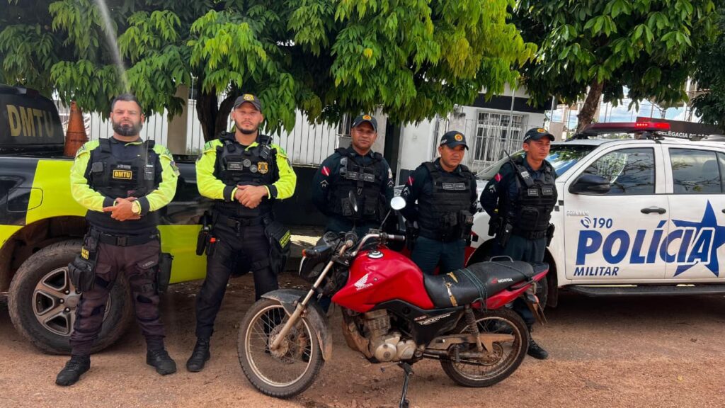 Policiais militares e moto Honda vermelha apreendida em operação.