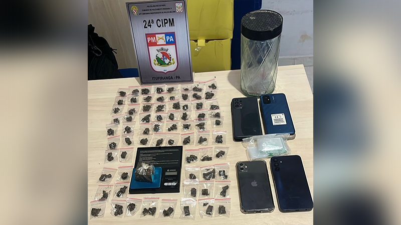 Mesa com dezenas de porções de drogas ilícitas, uma balança digital e quatro smartphones, com uma placa da Polícia Militar do Pará ao fundo.