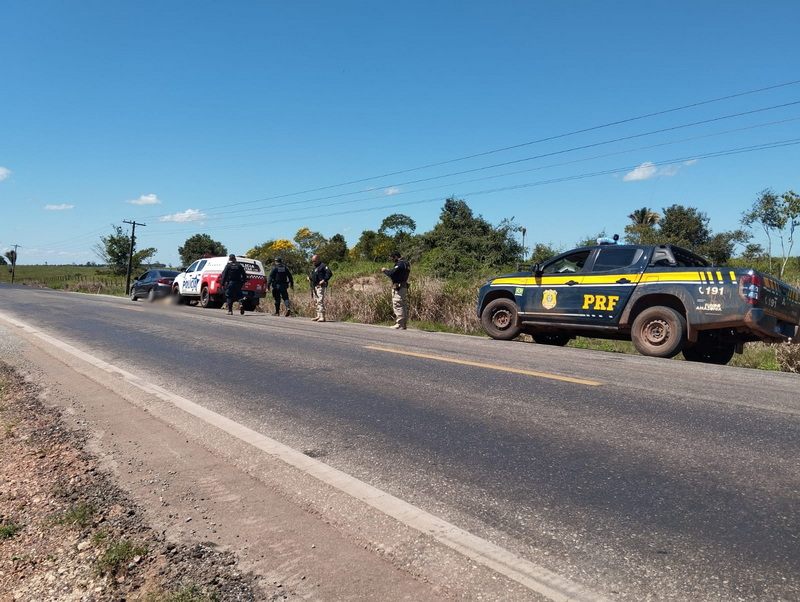 Policiais rodoviários federais e outros agentes em operação na beira de uma estrada rural.