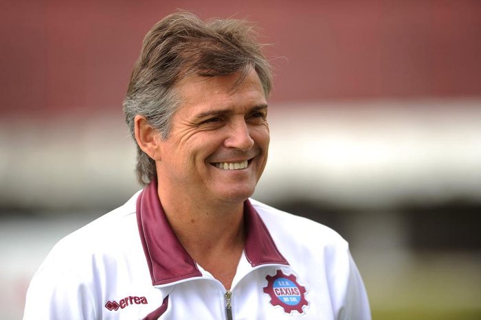 Homem sorrindo com camisa do Caxias do Sul e cabelo grisalho.