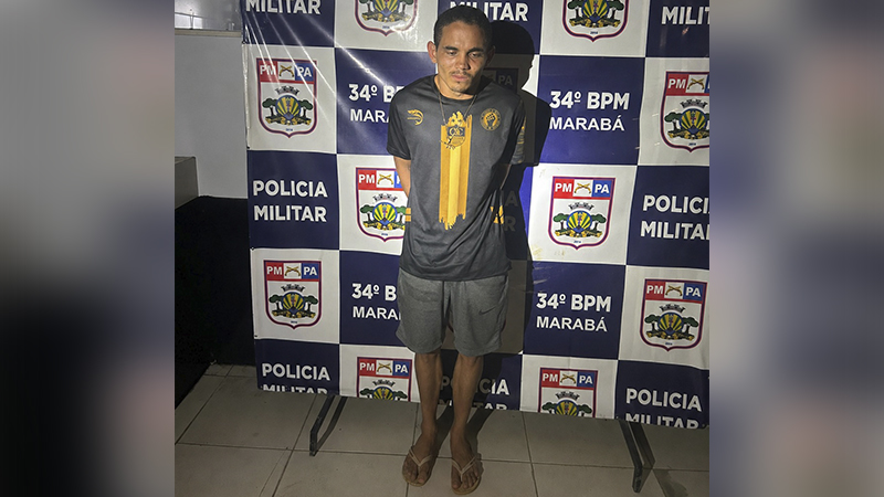 Homem em pé, de frente, em frente a um banner da Polícia Militar do Pará, 34º BPM Marabá.