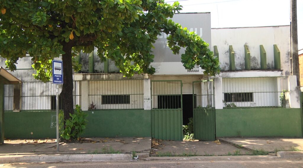 Fachada de um centro educacional em Marabá com portão verde aberto e árvore frondosa na frente.
