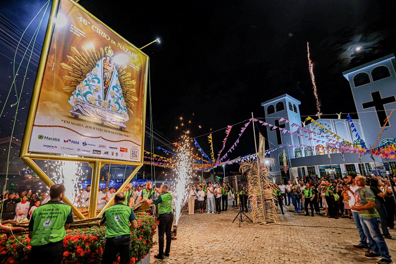 Celebração noturna do 46º Círio de Nazaré com grande banner da santa, fogos e multidão em frente à igreja.