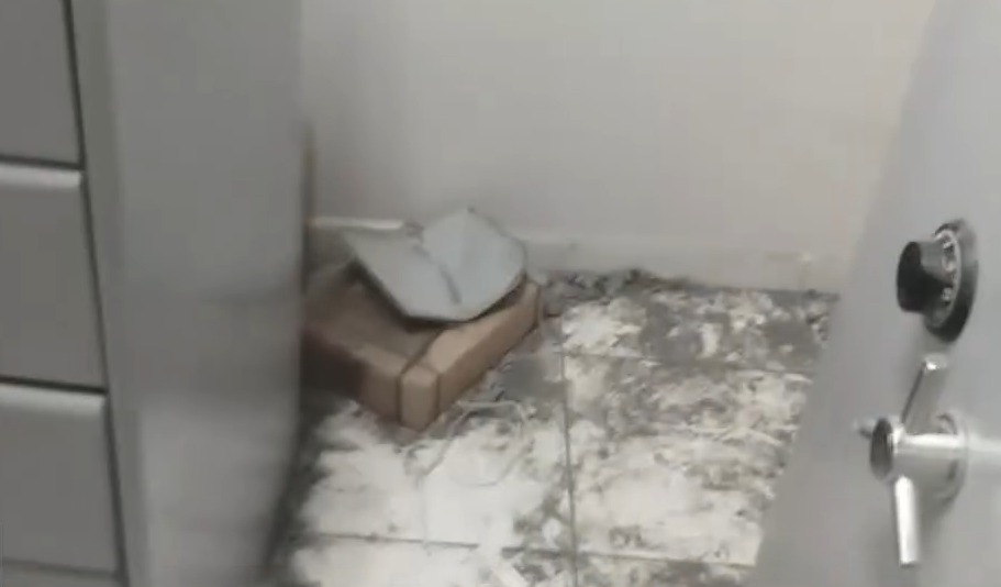 Piso sujo com acúmulo de poeira e detritos em um canto perto de um armário.