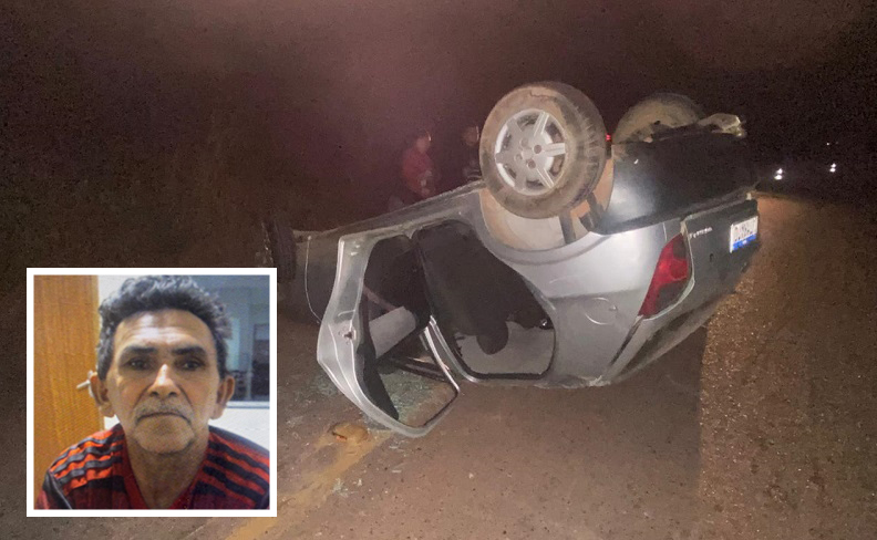 Carro capotado em estrada de terra à noite com foto de homem em destaque.
