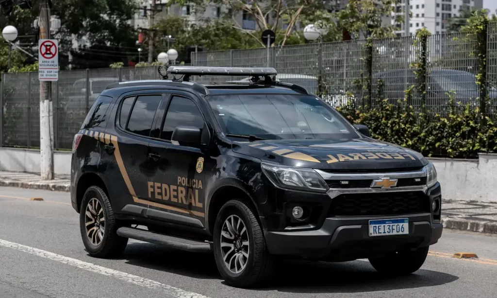 Viatura oficial da Polícia Federal em circulação em uma rua asfaltada