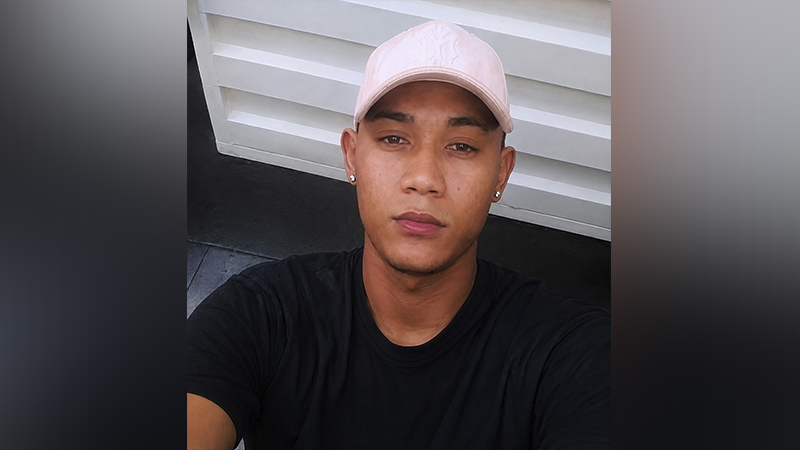 Jovem homem de pele morena vestindo boné rosa claro e camiseta preta.