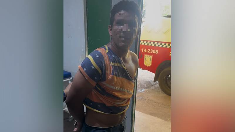 Homem detido com as mãos algemadas nas costas, vestindo camiseta listrada.