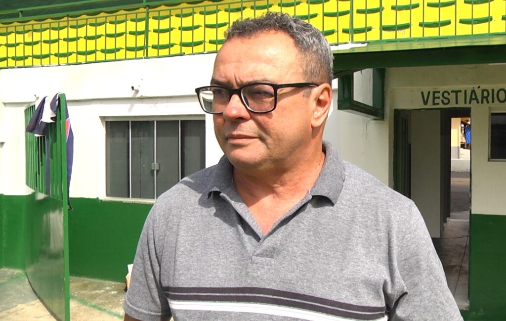 Homem de meia-idade com cabelos grisalhos e óculos posando ao ar livre.