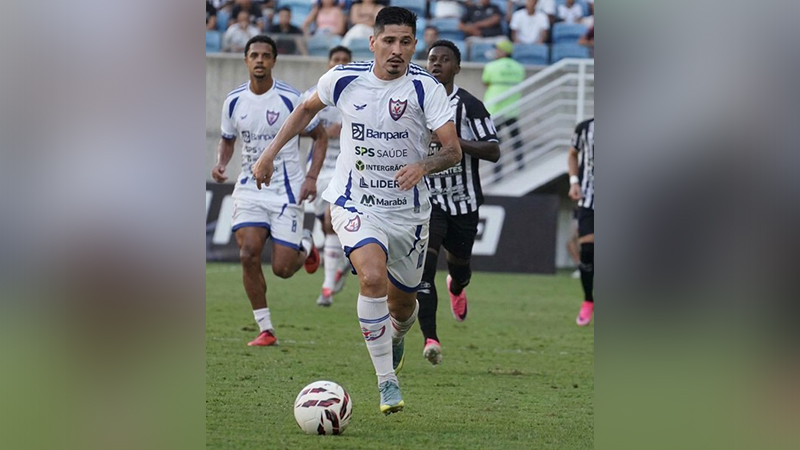 Jogador de futebol de branco correndo com a bola em campo
