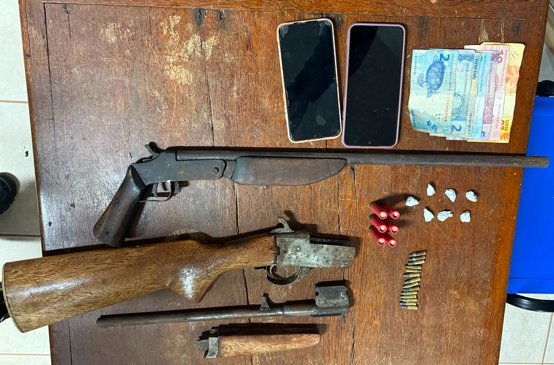 Apreensão policial de armas, munições e dinheiro sobre uma mesa