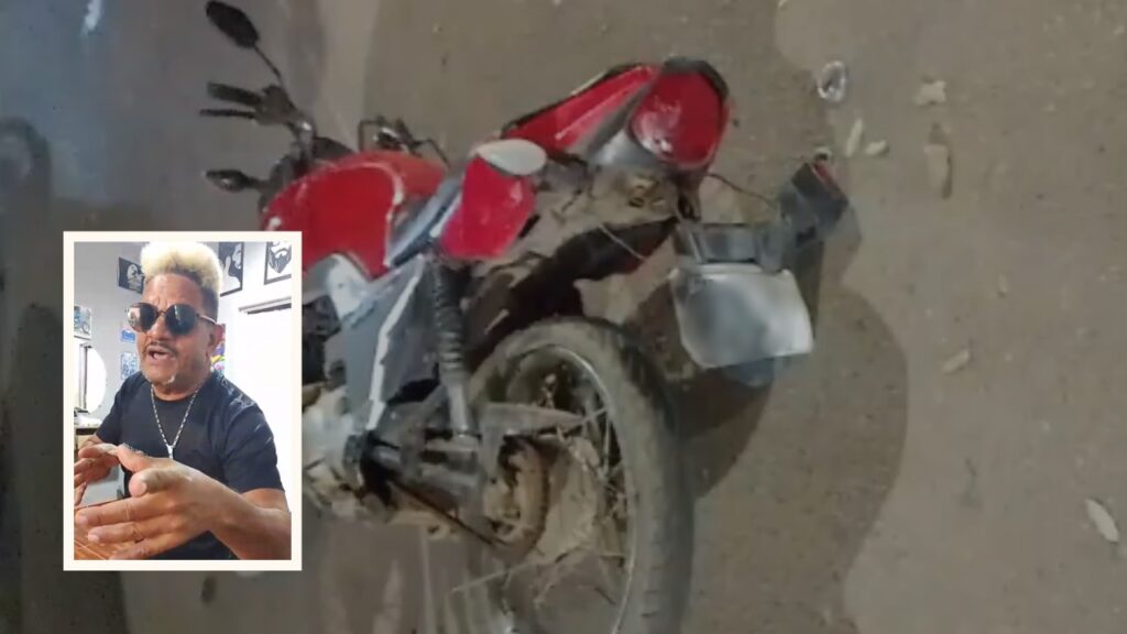 Motocicleta vermelha estacionada em piso de terra.