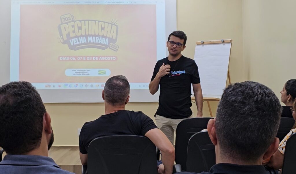 Homem apresentando palestra em frente a uma tela de projeção sobre o evento Pechincha Velha Marabá.