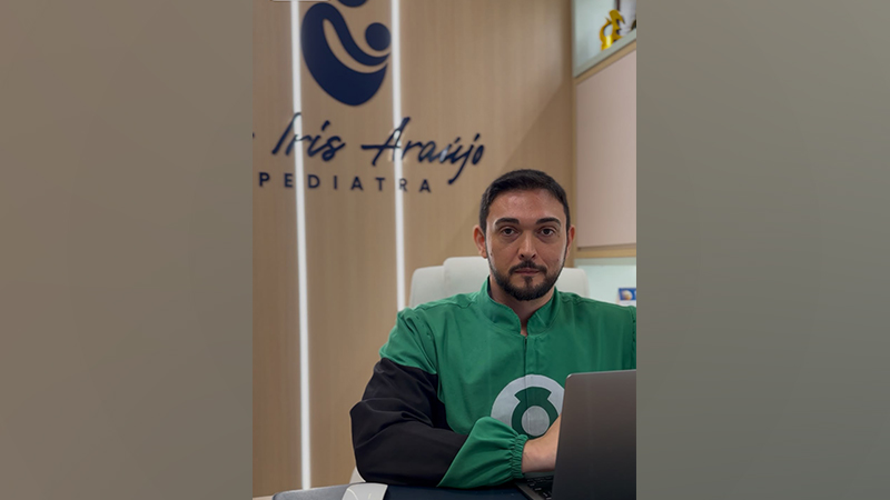 Médico pediatra sentado em seu consultório em frente ao computador