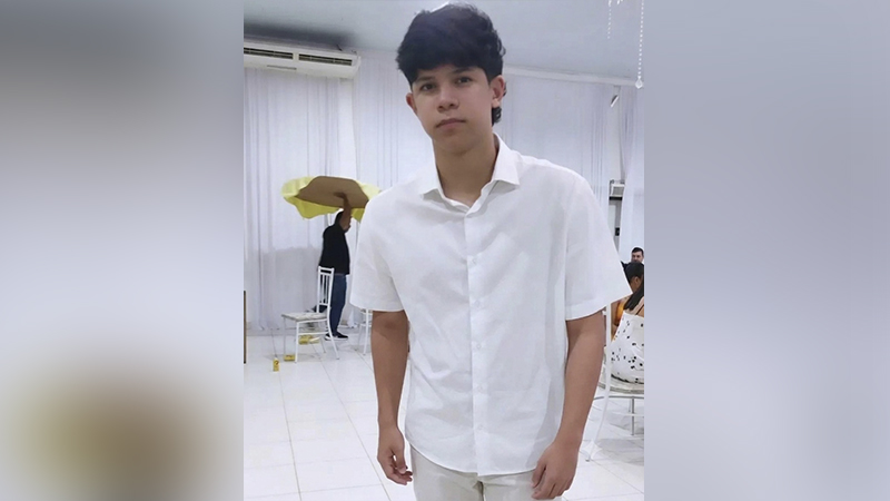 Jovem rapaz com cabelo escuro e camisa branca em uma festa